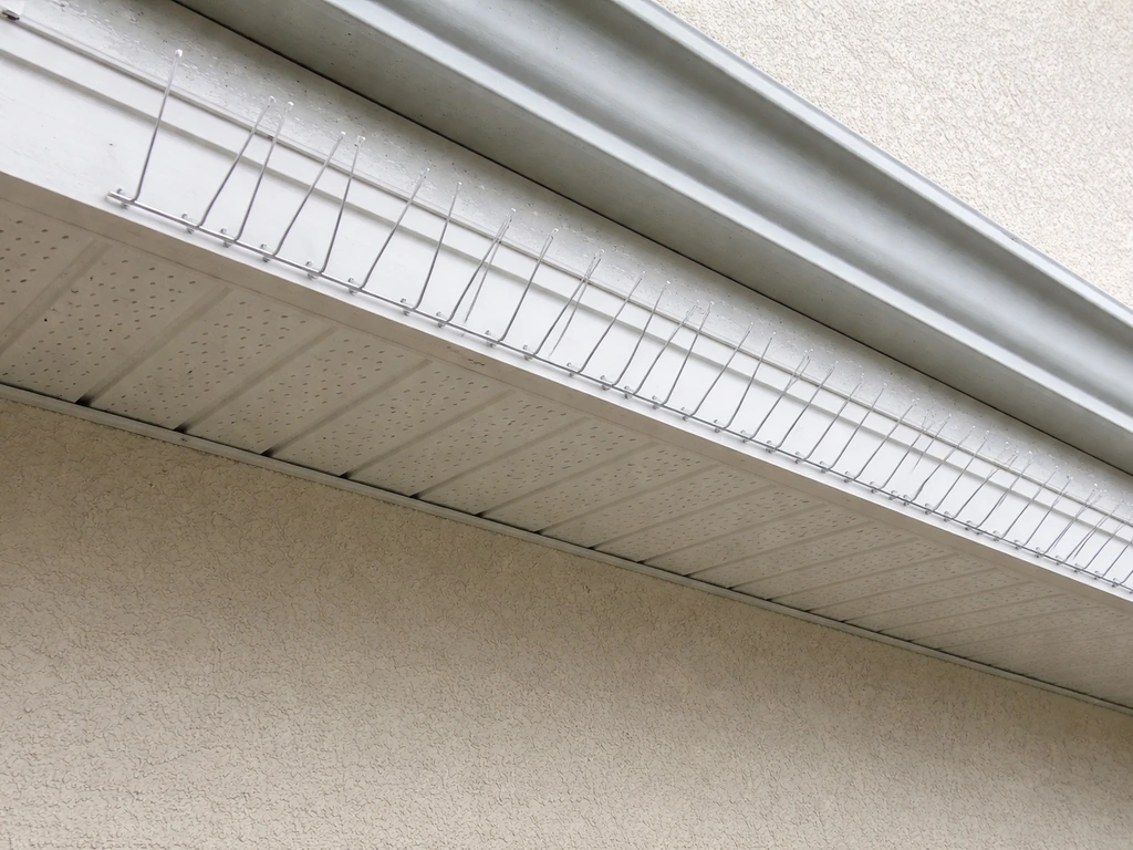Close-up of eave fascia/soffit edge with metal spikes installed in a straight, flush line.